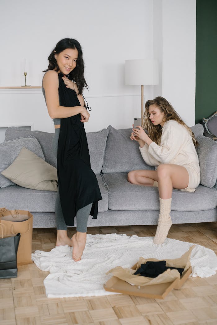 creative-01 Two women relaxing while trying on new clothing purchases in a cozy living room setting.