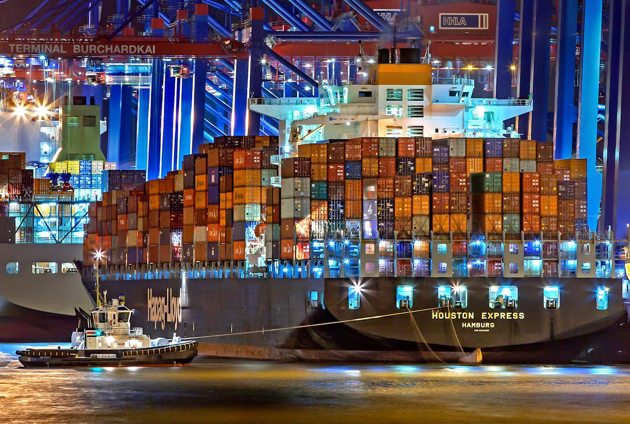creative A brightly lit cargo ship at Hamburg harbor with stacked containers and a tugboat.