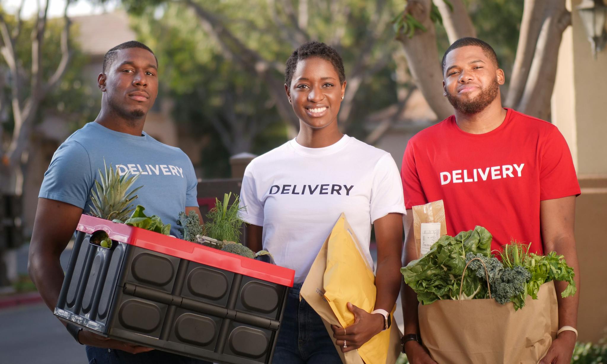 Home Diverse group delivering groceries and packages outdoors. Smiling and professional.
