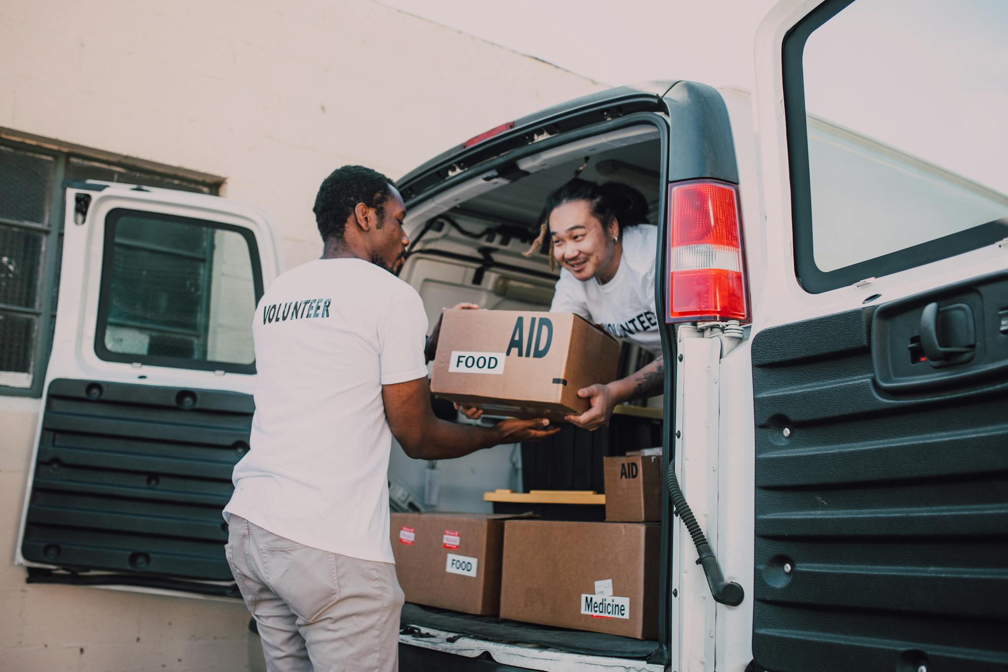 Home Volunteers unloading boxes of food and medicine from a van for community aid effort.